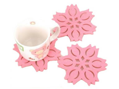 Three pink flower shaped wool felt coasters and a cup on the one coaster.