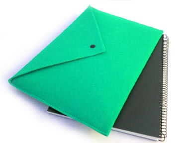 A green snap fastener wool felt document bag on a black notebook.