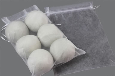 Eight wool dryer balls in an organza bag and another empty bag beside of it.