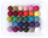 Several different colors felt balls in a plate.