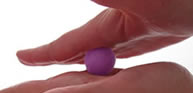 A pair of hands is rolling a pink wool felt ball.