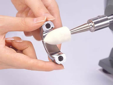 A pair of hands are polishing a metal accessory by the shaped wool felt bob.