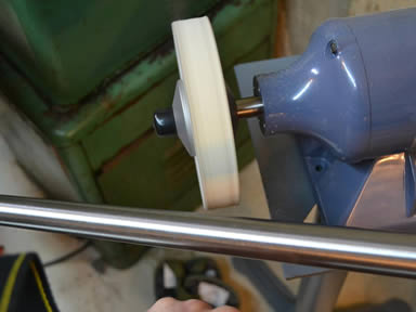 An operating machine is polishing a stainless steel tube with wool felt polishing wheel.