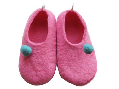 A pair of pink infant shoes with blue wool felt ball on the white background.